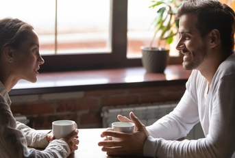 couple sitting in cafe talking drinking tea or coffee