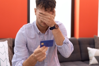 man holding credit card with worried expression 