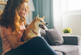 A happy woman with a dog she's pet sitting while house sitting