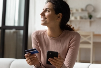 Smiling woman holding credit card and phone