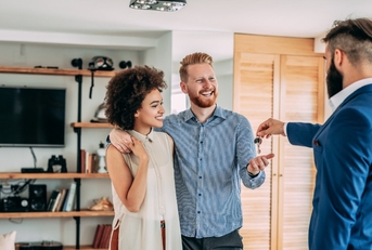 happy couple getting keys from realtor in suit