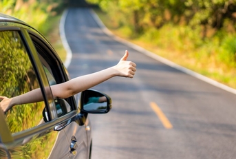 A driver on a two-lane road gives a thumbs up.