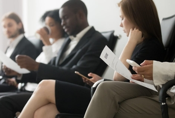 multi ethnic applicants waiting for their call using smartphones and holding papers