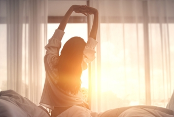 woman stretching hands in bed