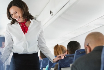 happy flight attendant passing through seats interacting with passengers