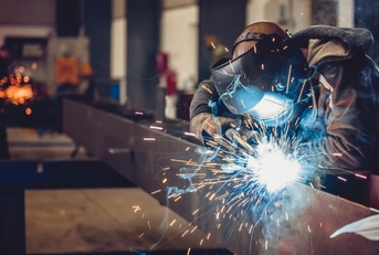 male worker using torch to weld metal at work