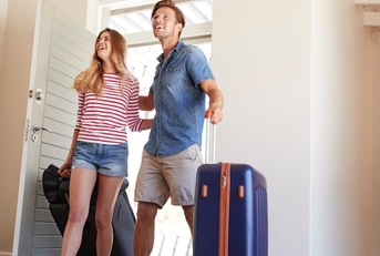 happy young couple with suitcases moving into new house
