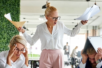 female boss angry at employees holding papers in hands at work