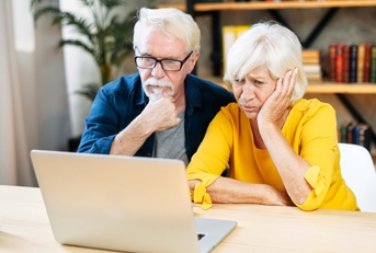 elderly couple is looking puzzled on the laptop screen