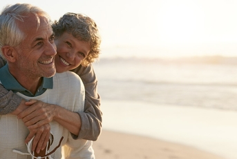 couple having each other back while smiling at beach