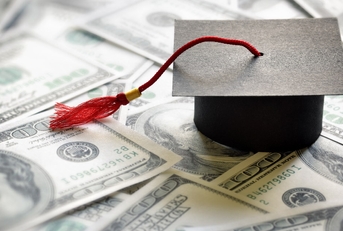 graduation cap on top of one hundred dollar bills  