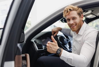 smiling man getting out of the car with a thumbs up