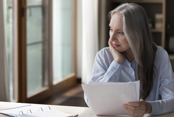 elderly retired woman thinking over paper documents