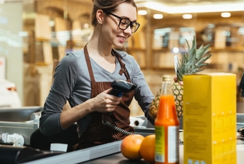 happy female cashier at store scanning grocery items