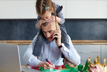 daughter sitting on her dads shoulders while he's working on his laptop