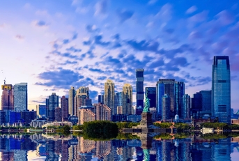 skylines of new jersey with statue of liberty in front of water under cloudy sky