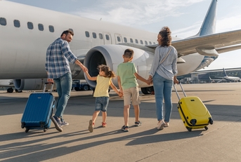 smiling parents and kids walking with travel bags