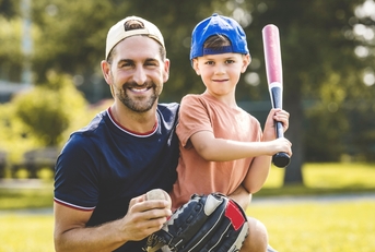 father and son playing baseball in sunny day at public park
