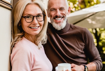 pleased senior couple smiling with cups of coffee