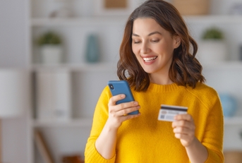 Very happy woman holding phone and credit card