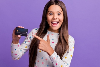 happy teenage girl smiling while pointing towards card in hand