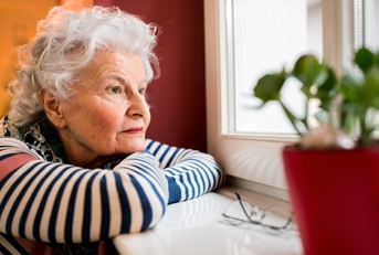 sad senior woman looking through window