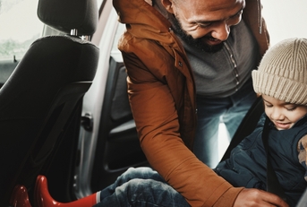 A father is keeping his child safe by using a seat belt