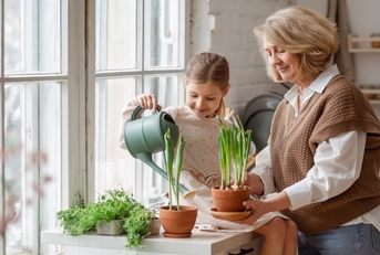 senior woman teaching young girl to care for potted plants
