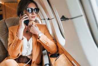 elegant woman wearing suit sitting on private jet talking on phone