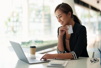 Happy women online banking on laptop holding debit card