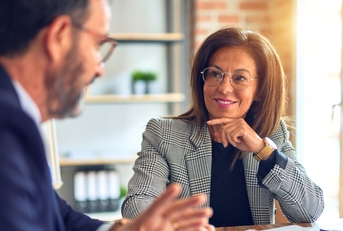 confident businessman explaining ideas to business woman sitting at table with papers in office