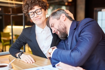 man in business suit leaning to a female colleague
