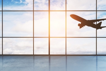 A plane seen taking off through the window of an airport. 