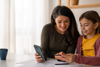 young woman using a mobile phone and a credit card with her daughter