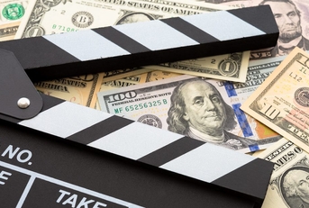 A movie clapboard on top of a pile of cash.