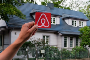 This image features the Airbnb logo and a city in the background, inviting you to travel the world with Airbnb.