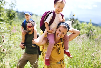  a couple,accompanied by their small children hiking outdoors during summer season