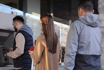 people waiting for their turn to use atm in street