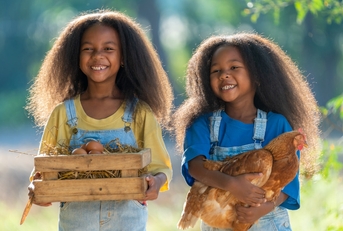 young girls holding eggs and chicken