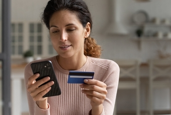 Smiling woman looking at phone and holding credit card