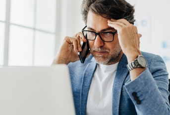 Stressed businessman having call at work
