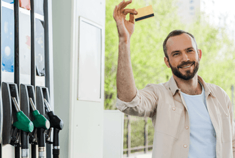 man holds credit card by gas pumps