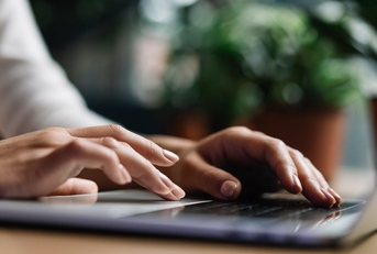 View of a person's hands typing on a laptop keyboard.