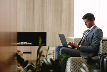 Executive sitting in an airport business lounge and is using his laptop while waiting for a flight.