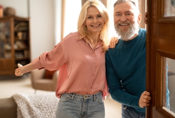 Happy senior couple holding opened door