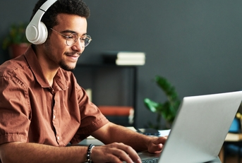 Man using laptop while wearing headphones