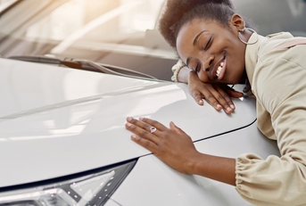 woman hugging car bonnet at showroom
