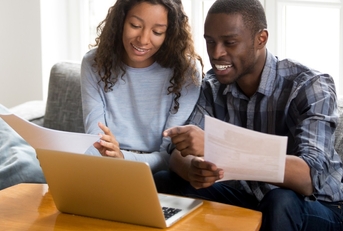 happy african american couple reviewing bills