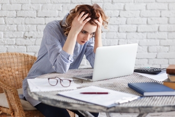 frustrated woman holding head with laptop