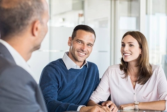 A businessman sitting at a table with two customers.
